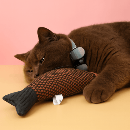 Brown cat snuggling squeaky catnip fish toy– Fun, Safe & Snuggly Playtime for Cats on a colorful surface.