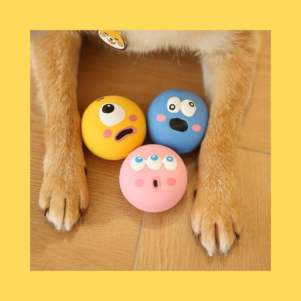 Squeaky Eyeball Dog Toy - colorful latex balls with expressive faces, durable and safe for small breeds, placed between dog's paws.
