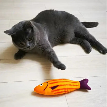 Grey cat playing with squeaky catnip fish toy– Fun, Safe & Snuggly Playtime for Cats, orange fish-shaped toy on floor.